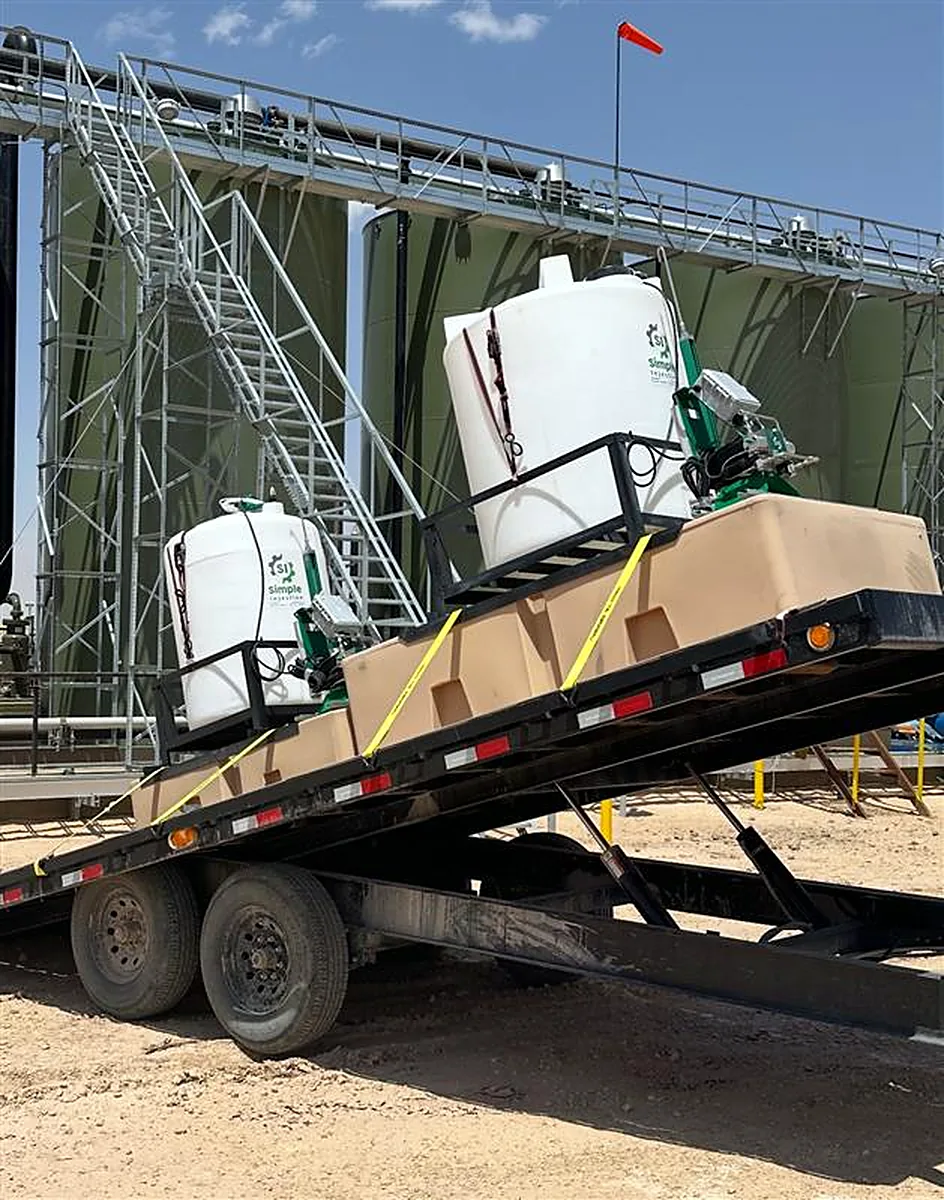 Chemical injection skid being unloaded next to a tank battery