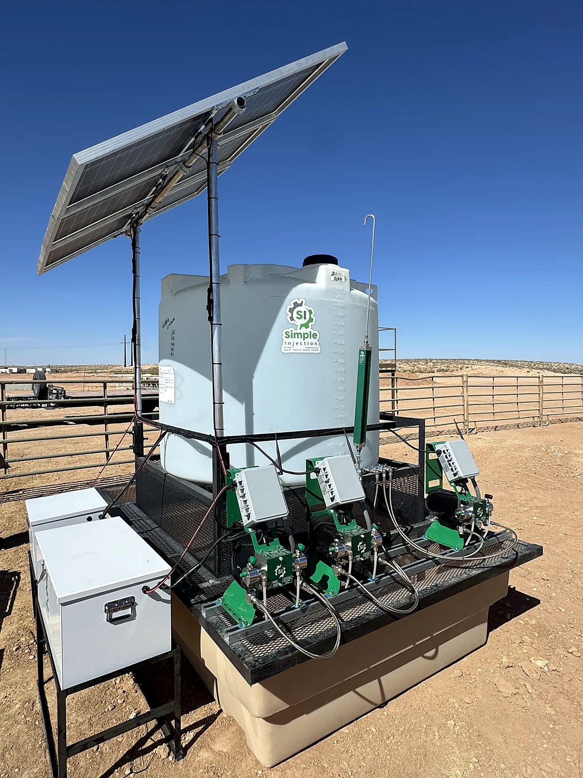 Chemical injection skid with solar panel, storage tank, secondary containment and three pumps at a wellsite