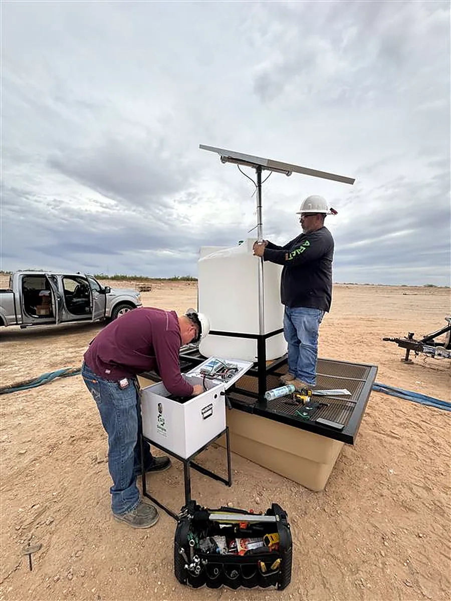 Technicians servicing a solar powered chemical injection skid at a wellsite